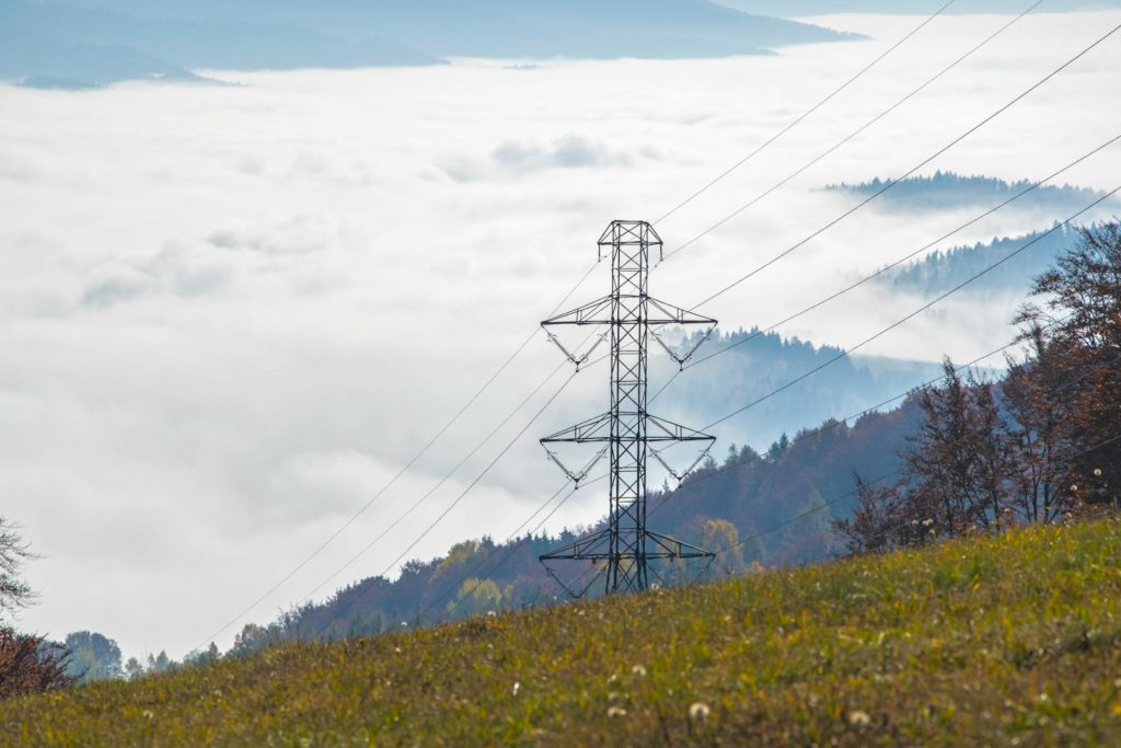 High voltage power tower in a foggy mountain landscape creating a dramatic scene.