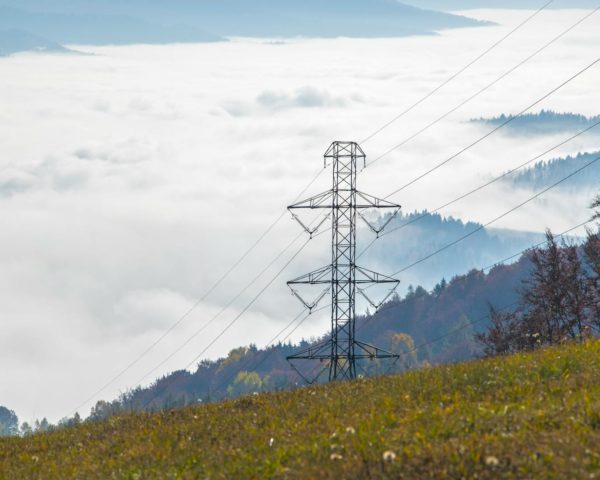 High voltage power tower in a foggy mountain landscape creating a dramatic scene.